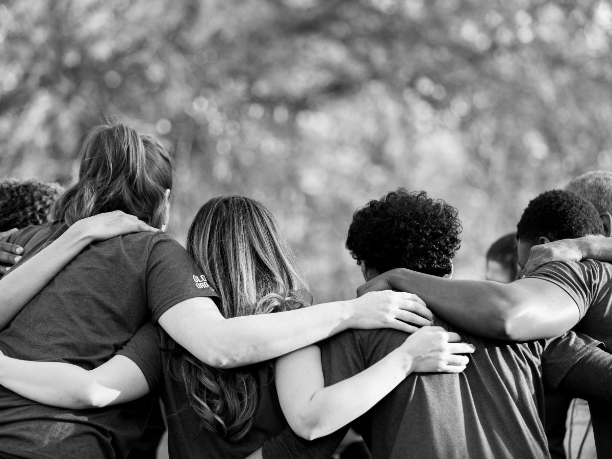 A diverse group of people standing together with their arms around each other
